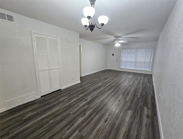 interior space with ceiling fan with notable chandelier, dark wood-type flooring, and a textured ceiling