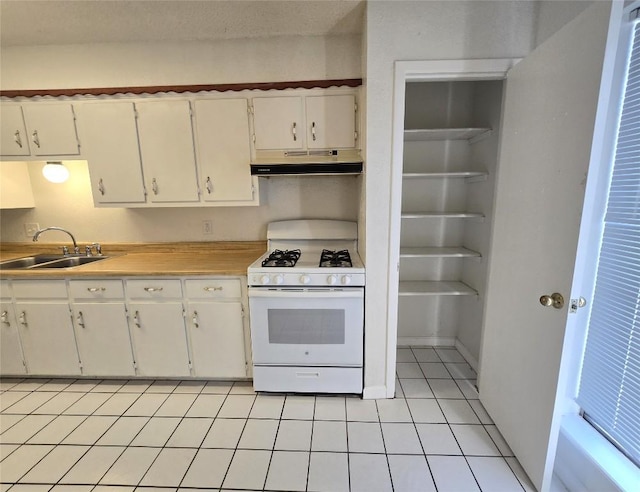 kitchen with white cabinetry, white gas range, light tile patterned floors, and sink