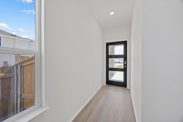 doorway with baseboards and wood finished floors