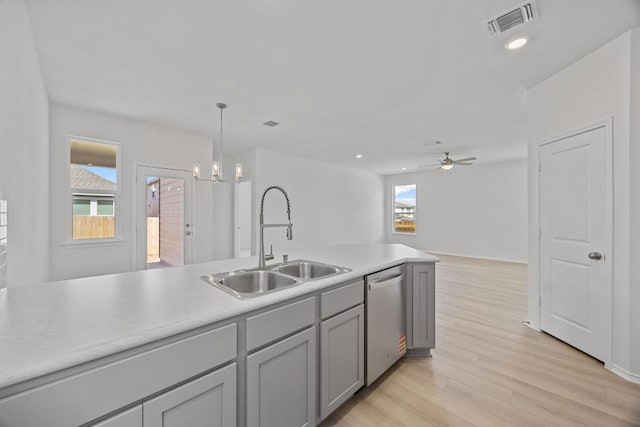 kitchen featuring visible vents, gray cabinetry, stainless steel dishwasher, a sink, and light wood-type flooring