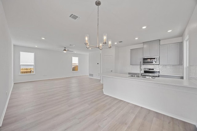 kitchen featuring stainless steel appliances, a sink, visible vents, backsplash, and gray cabinets