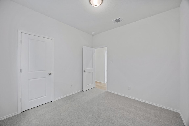 spare room with carpet, visible vents, and baseboards