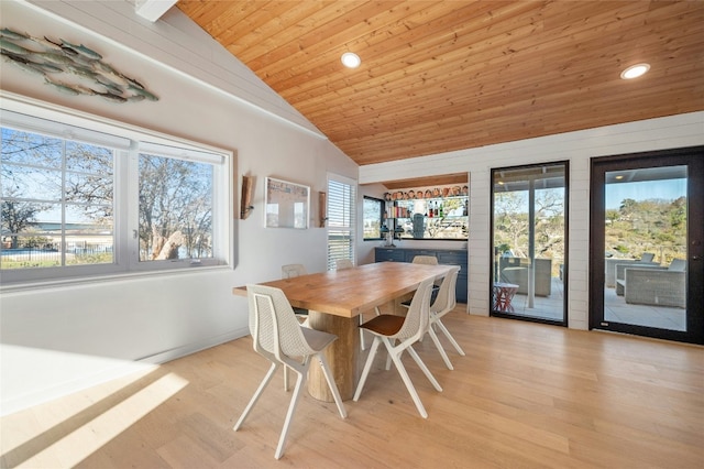 dining space featuring lofted ceiling, light wood-type flooring, wooden ceiling, and bar area