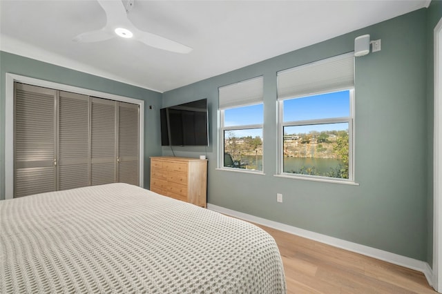 bedroom with a closet, light hardwood / wood-style flooring, and ceiling fan