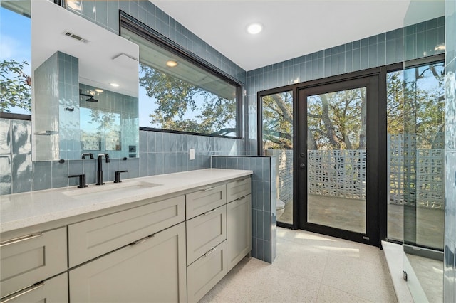 bathroom with plenty of natural light, toilet, tile walls, and vanity