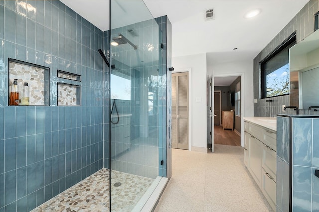 bathroom featuring a tile shower and vanity