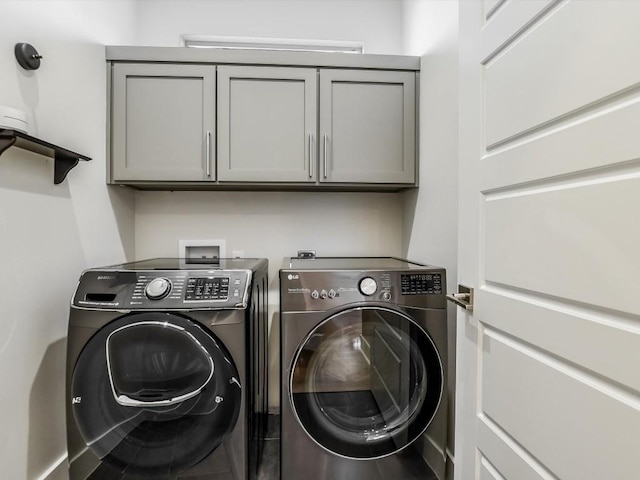 clothes washing area featuring washer and clothes dryer and cabinets