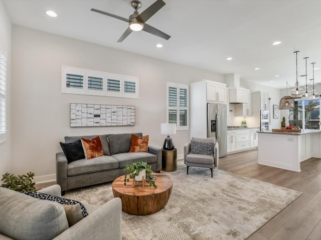 living room with light wood-type flooring, plenty of natural light, and ceiling fan