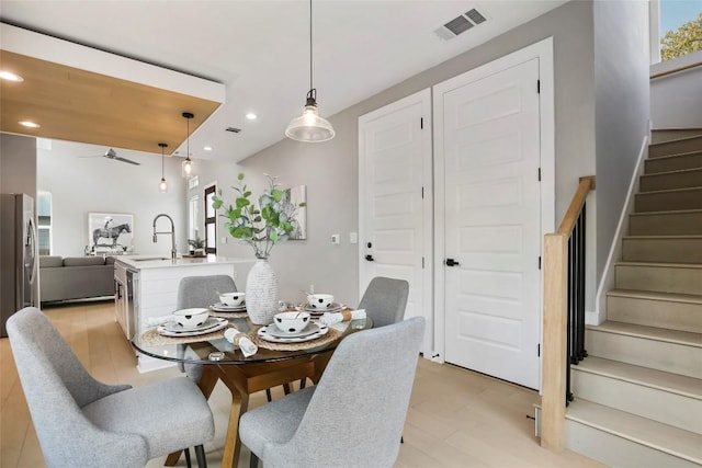 dining space with ceiling fan, sink, and light hardwood / wood-style flooring