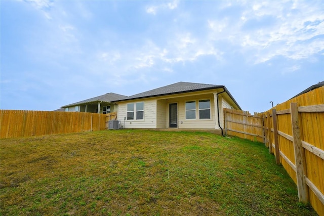 rear view of property featuring a yard and cooling unit