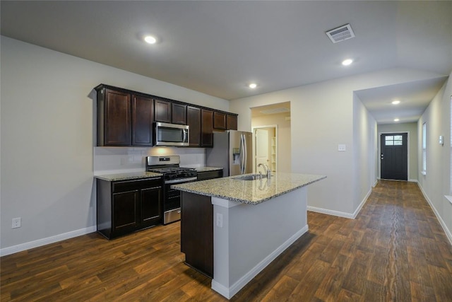 kitchen with light stone countertops, dark hardwood / wood-style flooring, stainless steel appliances, a kitchen island with sink, and sink