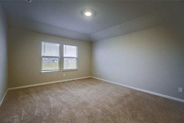 carpeted empty room with vaulted ceiling