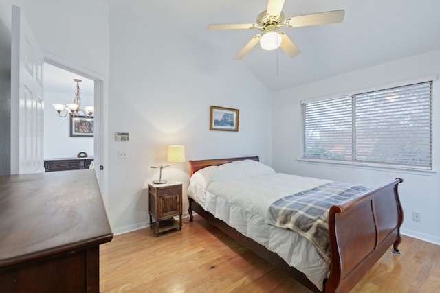 bedroom featuring ceiling fan with notable chandelier, lofted ceiling, and light hardwood / wood-style flooring