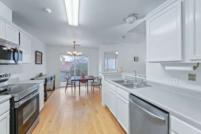 kitchen with a chandelier, stainless steel appliances, white cabinetry, and sink