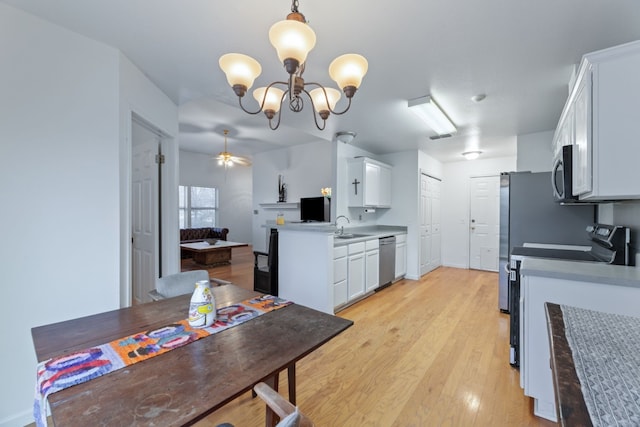 kitchen featuring light hardwood / wood-style floors, white cabinetry, hanging light fixtures, and stainless steel appliances