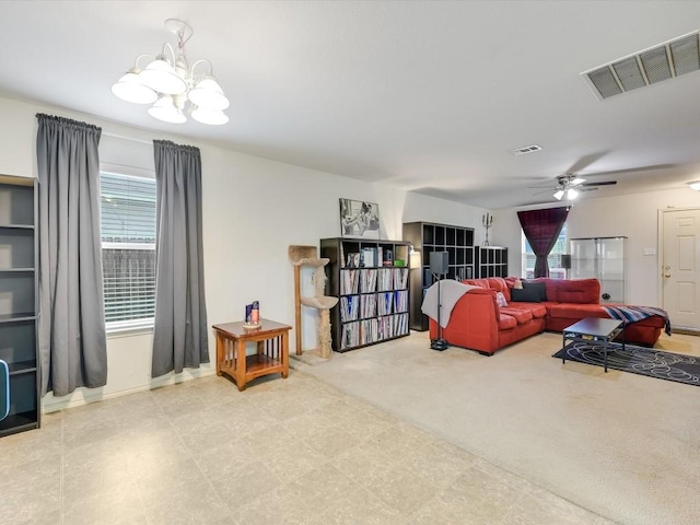 carpeted living room with ceiling fan with notable chandelier and plenty of natural light