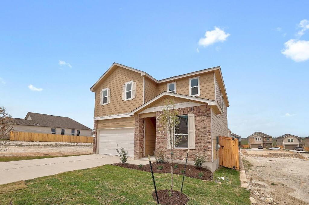 traditional home featuring fence, a front lawn, brick siding, a garage, and concrete driveway
