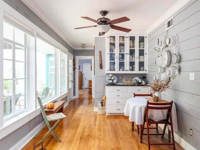 interior space featuring white cabinetry, light hardwood / wood-style flooring, ceiling fan, and ornamental molding