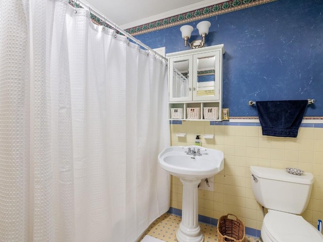 bathroom with toilet, crown molding, and tile walls