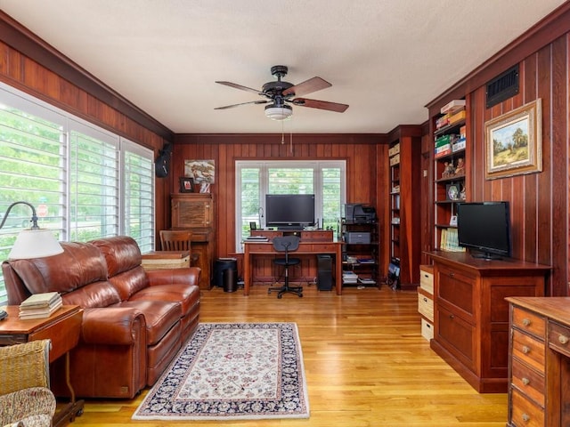 home office with crown molding, ceiling fan, wooden walls, and light hardwood / wood-style floors