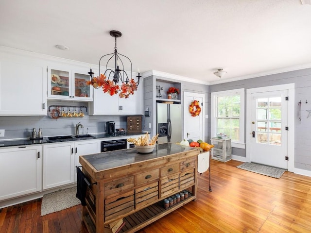 kitchen featuring white cabinetry, a notable chandelier, stainless steel fridge, wood-type flooring, and pendant lighting