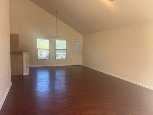 unfurnished living room featuring ceiling fan with notable chandelier, dark hardwood / wood-style flooring, and high vaulted ceiling