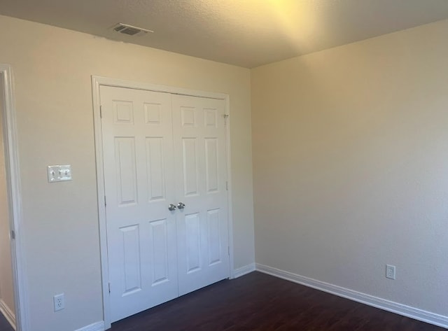 unfurnished bedroom featuring dark hardwood / wood-style flooring and a closet