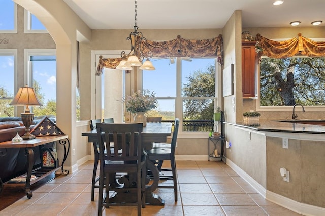 tiled dining area with a chandelier, a wealth of natural light, and sink