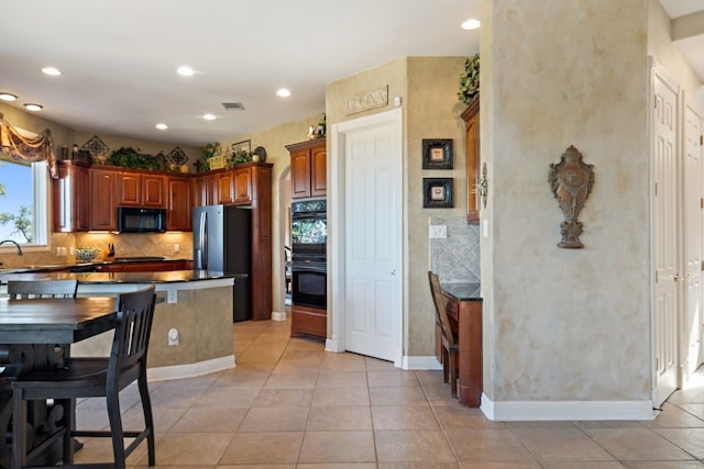 kitchen with light tile patterned floors, sink, tasteful backsplash, and black appliances