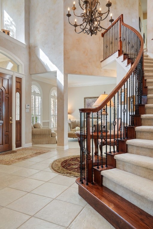 foyer entrance with crown molding, a towering ceiling, and an inviting chandelier