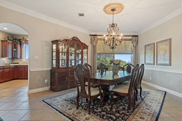 tiled dining room with ornamental molding and a chandelier