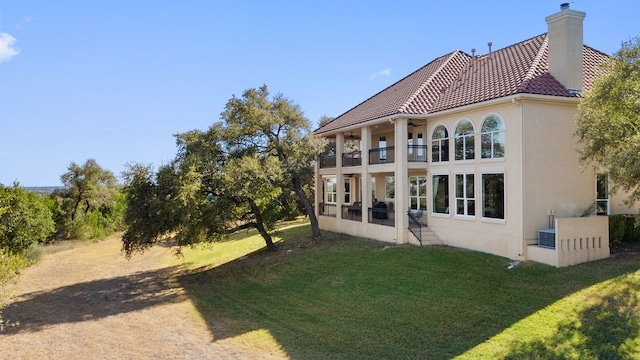 back of property with a yard and a balcony