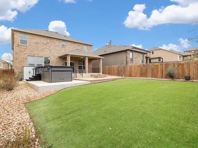 rear view of property featuring a patio area, a hot tub, and a yard