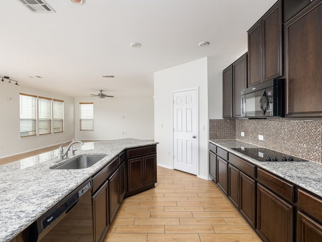 kitchen with light stone countertops, black appliances, ceiling fan, dark brown cabinets, and sink