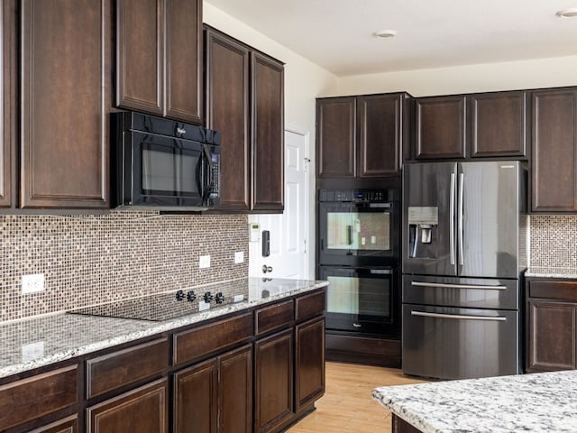 kitchen featuring light stone counters, light hardwood / wood-style flooring, black appliances, decorative backsplash, and dark brown cabinets