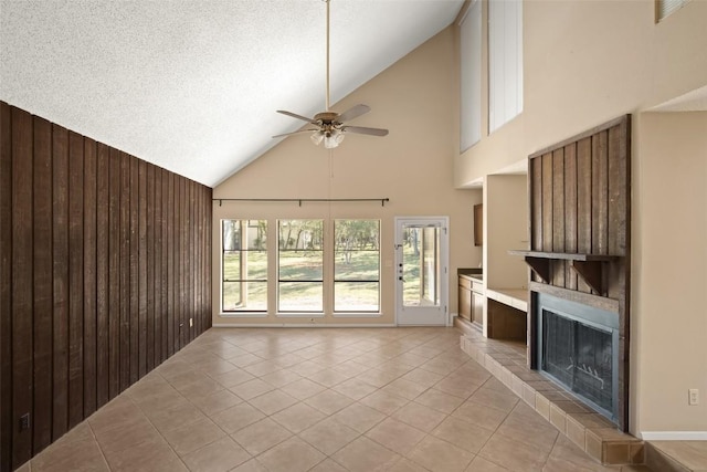 unfurnished living room featuring wood walls, a fireplace, ceiling fan, and light tile patterned flooring