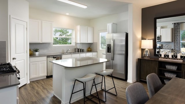 kitchen with sink, white cabinetry, a center island, appliances with stainless steel finishes, and decorative backsplash