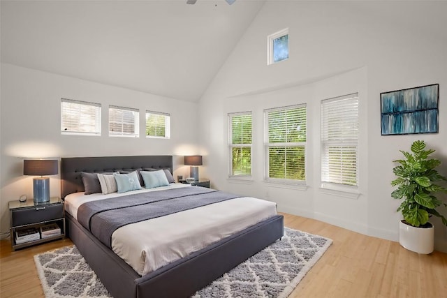 bedroom featuring ceiling fan, light hardwood / wood-style flooring, and high vaulted ceiling