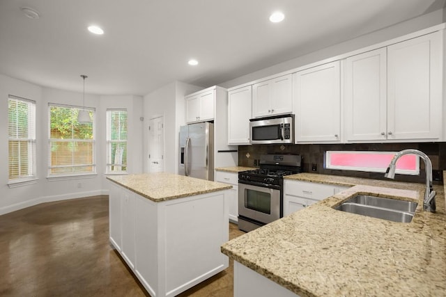 kitchen with white cabinets, sink, hanging light fixtures, appliances with stainless steel finishes, and a kitchen island