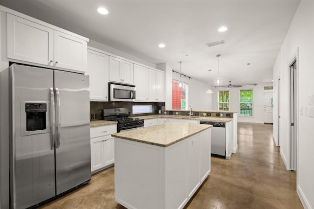 kitchen featuring ceiling fan, a center island, kitchen peninsula, pendant lighting, and appliances with stainless steel finishes