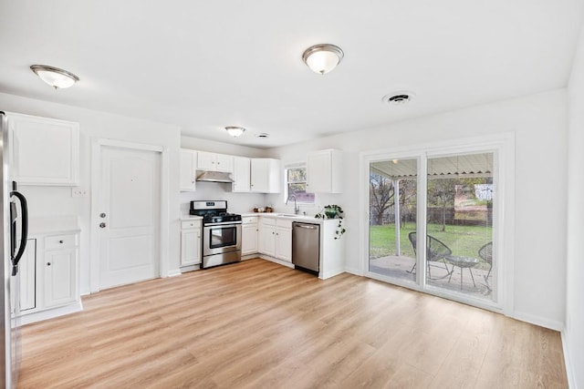 kitchen with white cabinets, appliances with stainless steel finishes, and light hardwood / wood-style flooring