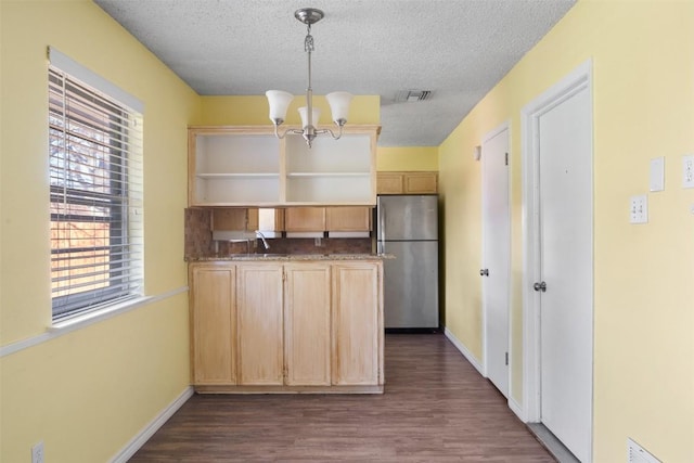 kitchen featuring stainless steel fridge, light brown cabinetry, a textured ceiling, pendant lighting, and a chandelier