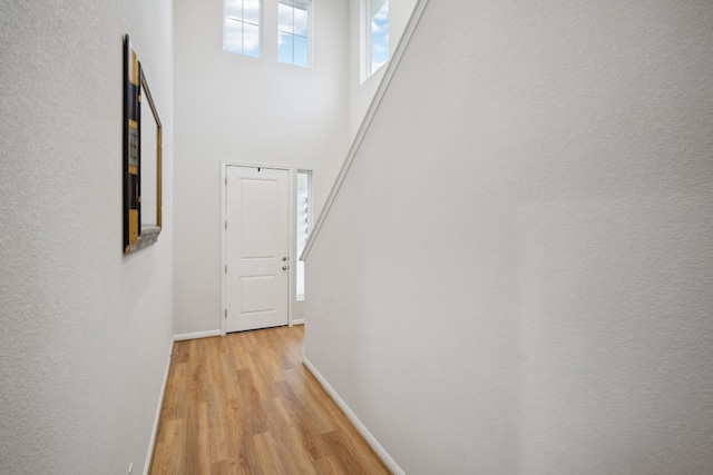 corridor with light hardwood / wood-style floors and a high ceiling