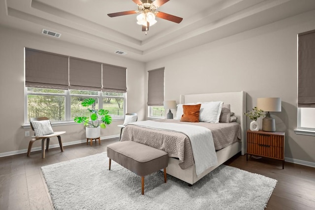 bedroom featuring ceiling fan, a raised ceiling, and dark wood-type flooring