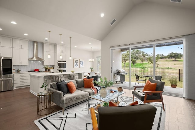 living room with hardwood / wood-style flooring, sink, and high vaulted ceiling