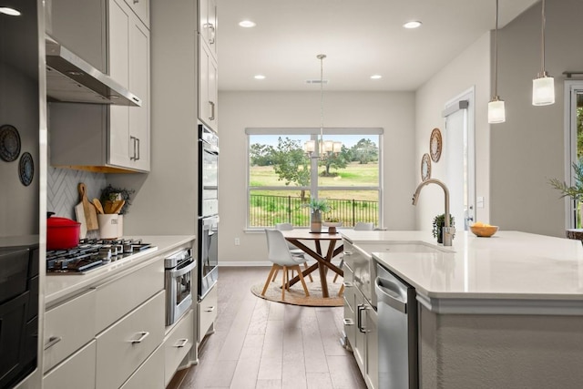 kitchen featuring a center island with sink, pendant lighting, white cabinetry, and stainless steel appliances