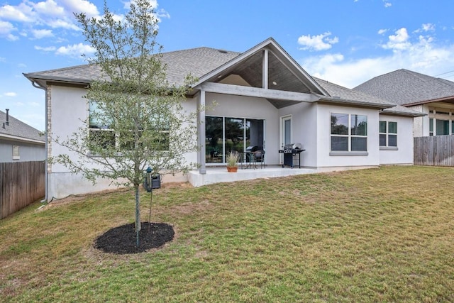 rear view of house featuring a lawn and a patio