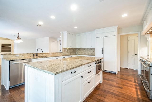 30102 Carmel Bay St, Georgetown, TX 78628 - kitchen with stainless steel appliances, a peninsula, tasteful backsplash, a kitchen island, and white cabinetry