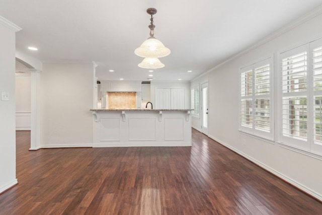 30102 Carmel Bay St, Georgetown, TX 78628 - kitchen with ornamental molding, dark wood-style flooring, a peninsula, light stone counters, and white cabinets