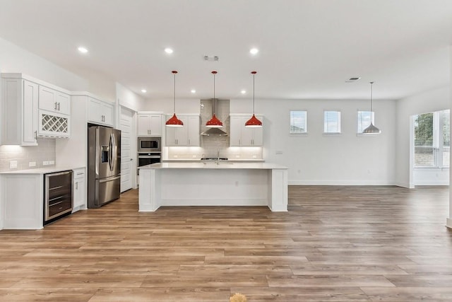 kitchen with wall chimney exhaust hood, hanging light fixtures, stainless steel appliances, and wine cooler